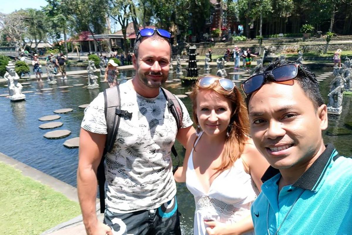 dva moška in ženska stojita pred vodnjakom