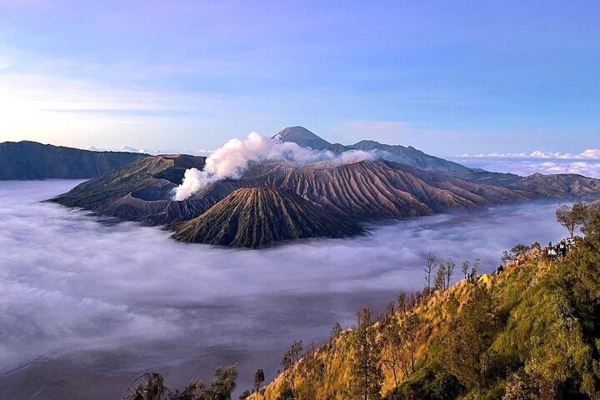 an island in the ocean with smoke coming from a volcano
