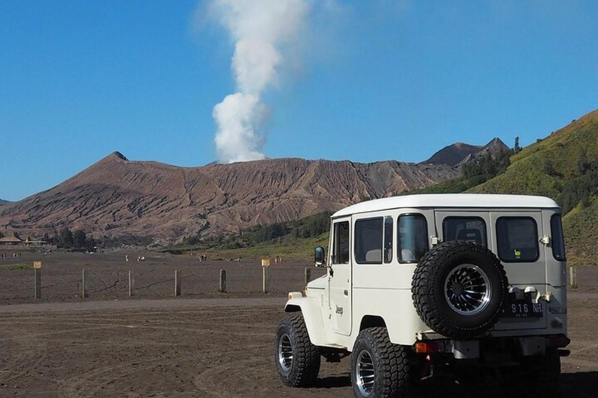 a white jeep parked on a dirt road with a smoke stack
