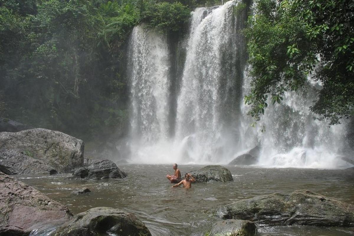 Tveir menn í vatninu fyrir framan foss