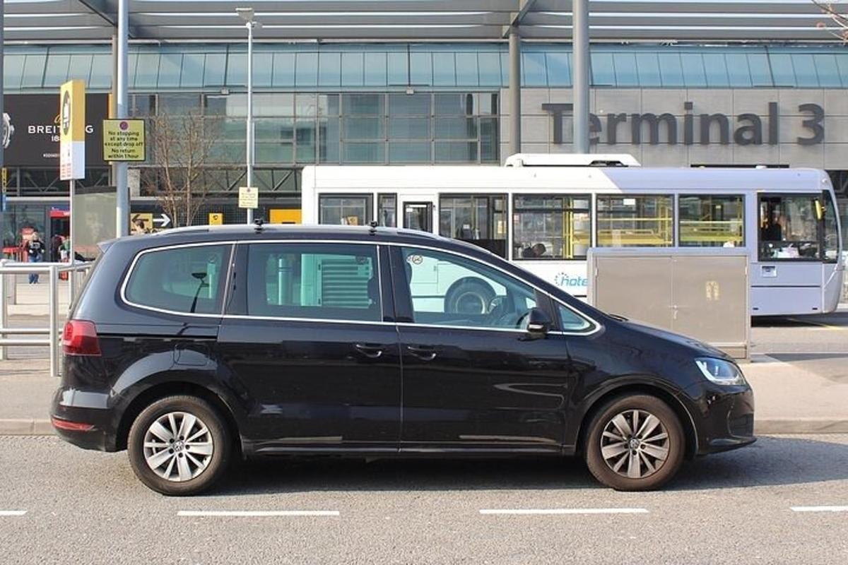 crni automobil parkiran na parkiralištu s autobusom