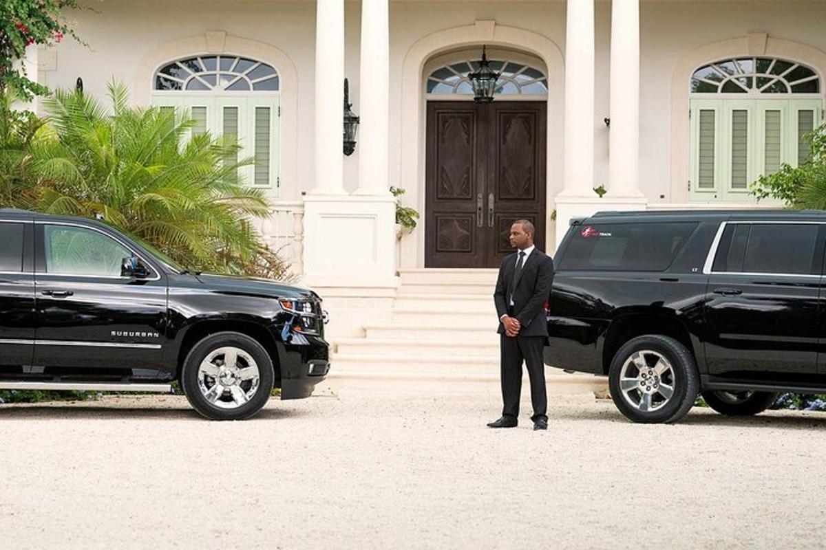 một người đàn ông mặc vest đứng cạnh một chiếc xe limo màu đen