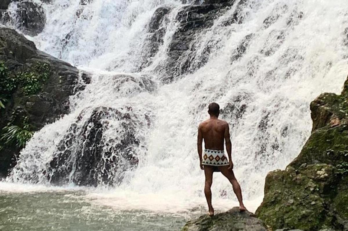 un home dret sobre una roca davant d'una cascada