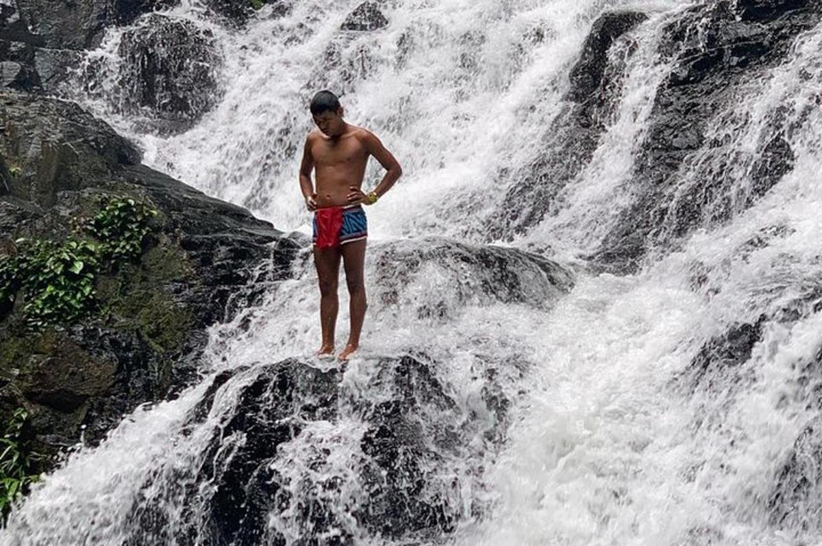 un uomo in piedi su una roccia di fronte a una cascata