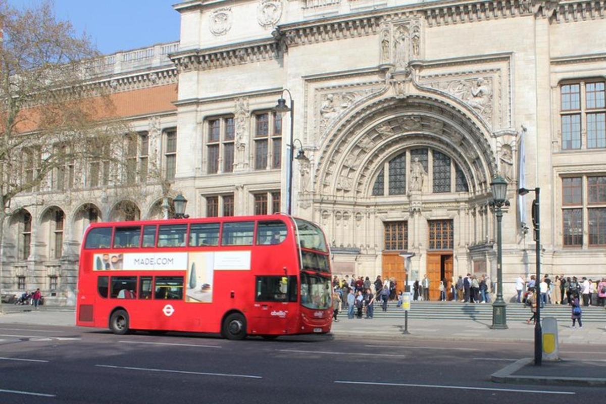 a red double decker bus driving past a building