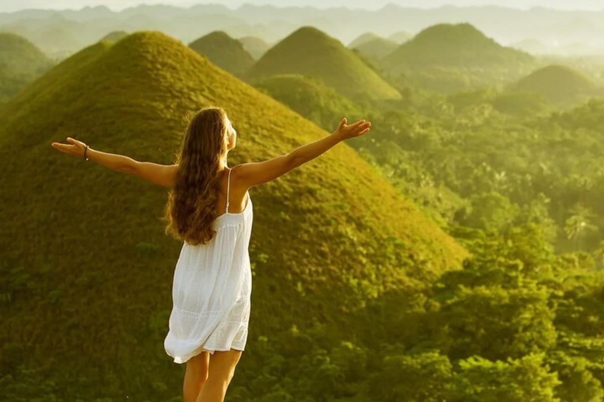 một người phụ nữ đứng trên đỉnh đồi với hai tay dang rộng