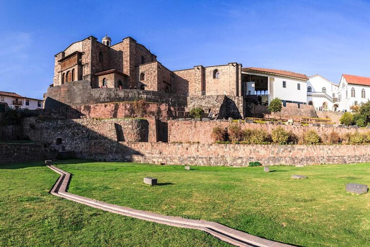 Un antiguo castillo con un campo de hierba delante.