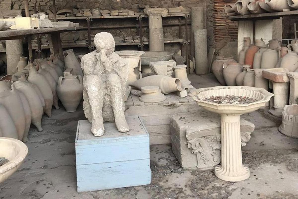 a statue of a person standing on a box in a room with vases