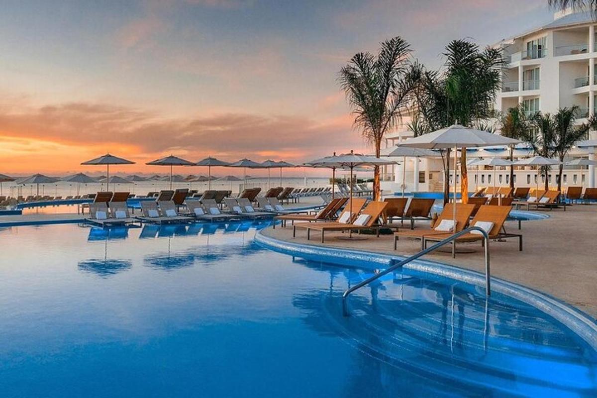 a hotel swimming pool with chairs and umbrellas