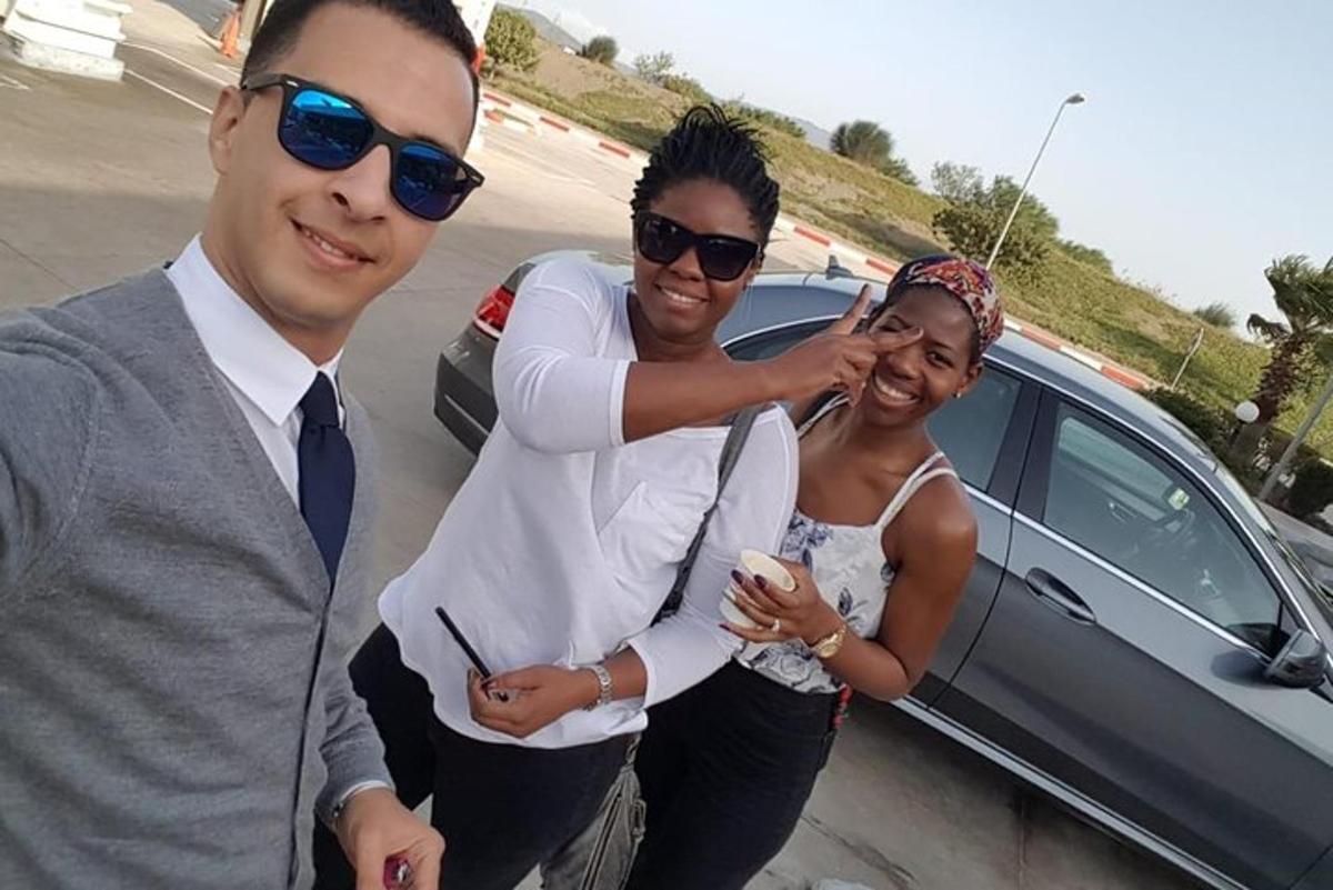 a man and two women standing next to a car
