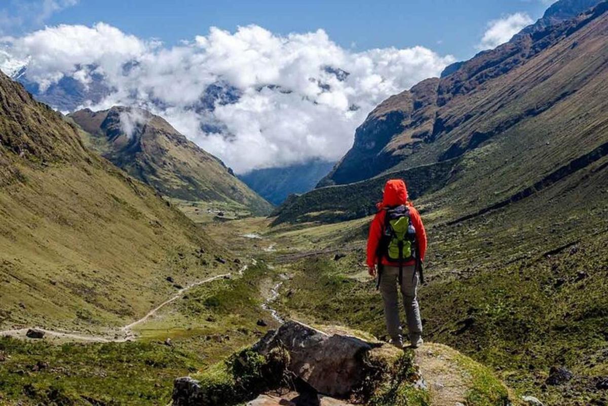 seseorang dengan beg galas berdiri di atas gunung