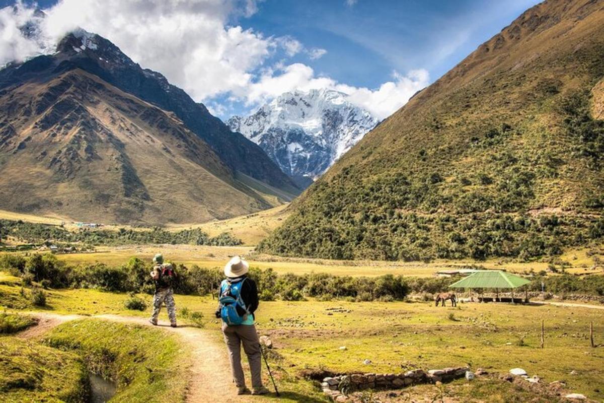 dues persones dempeus en un camí de terra mirant una muntanya