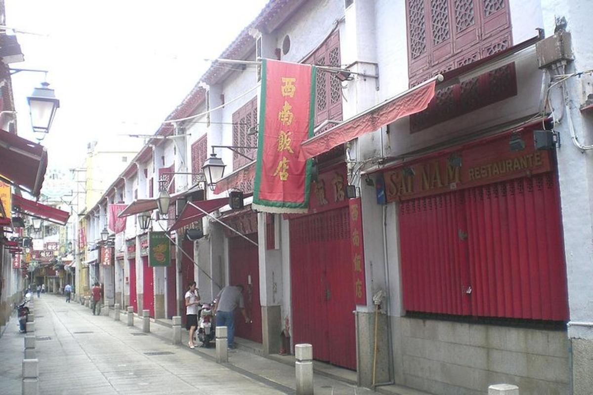 a street with buildings with red doors and people walking on the sidewalk