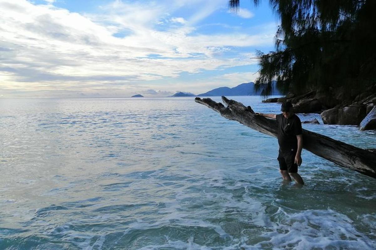 a man standing in the water next to a tree branch