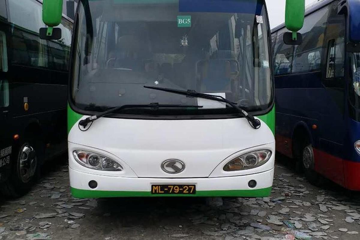 um ônibus branco e verde estacionado ao lado de outros ônibus