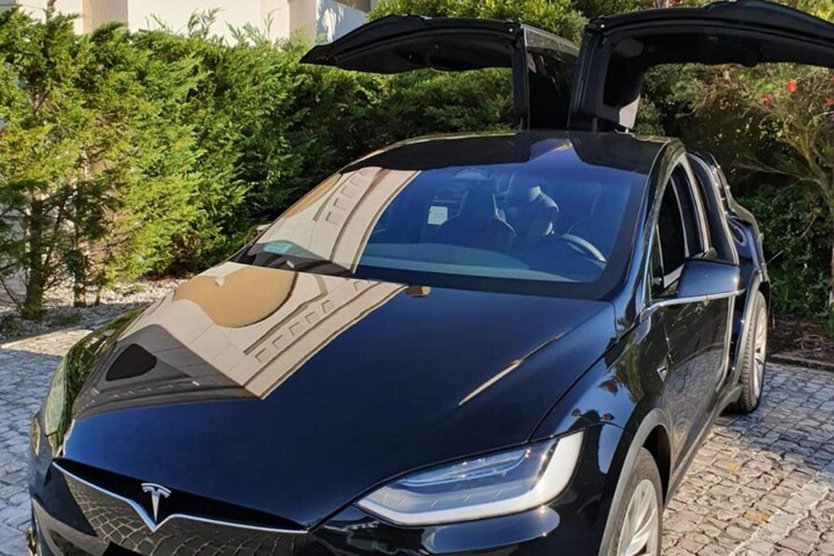 un'auto blu con le portiere aperte su una strada