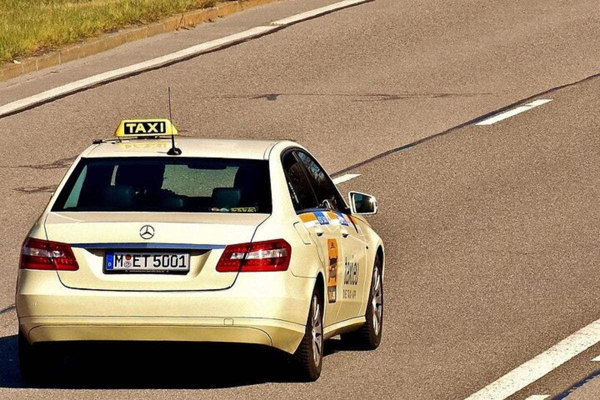 a car with a taxi sign on the roof on a highway