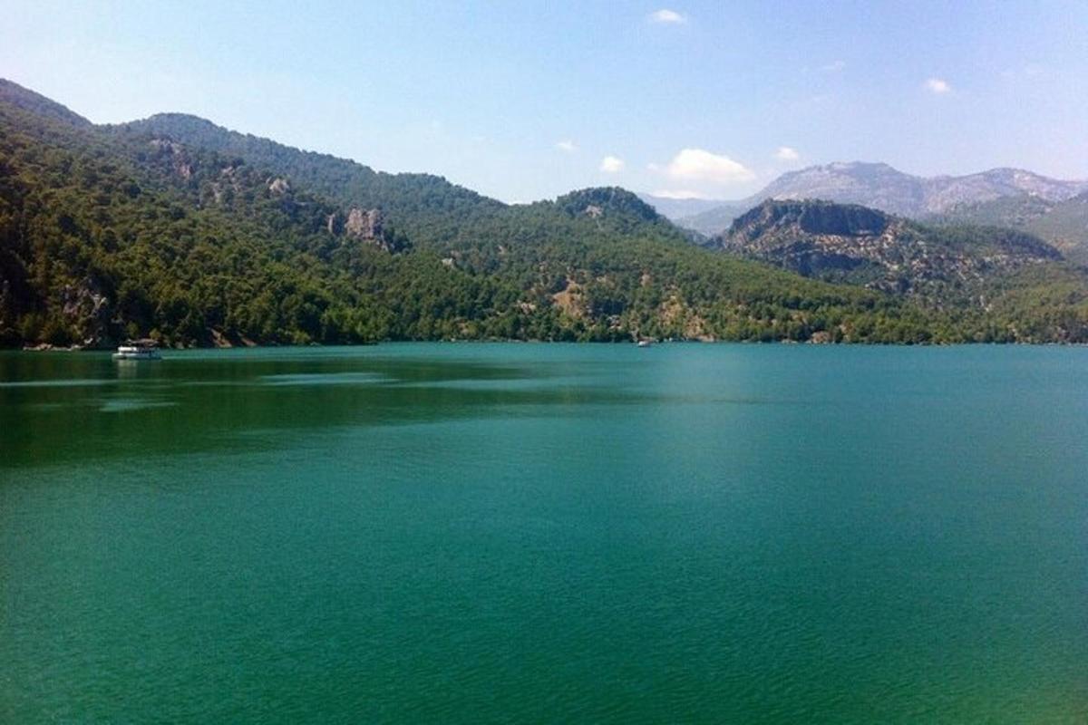 Un gran lago verde con montañas al fondo.