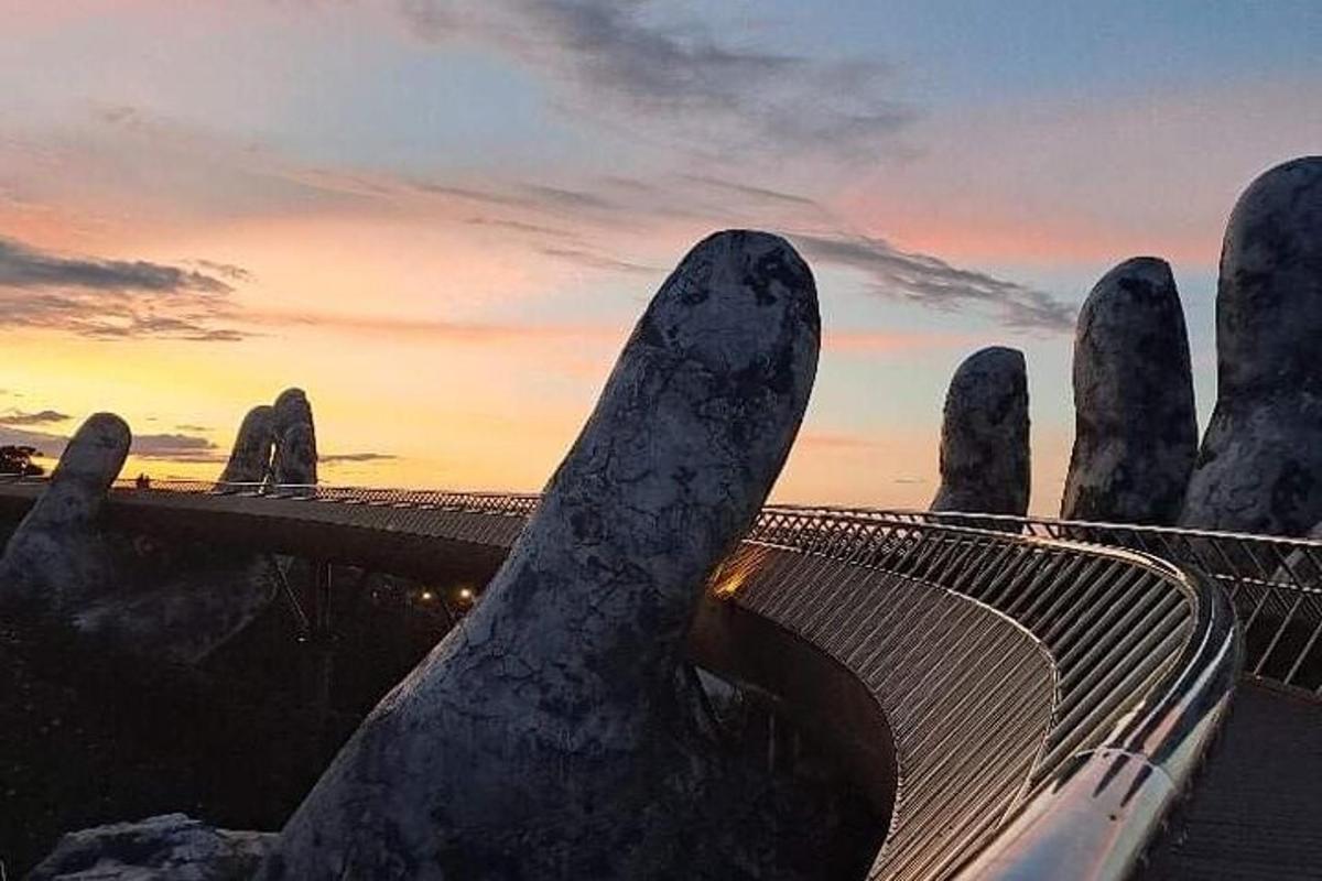 un gruppo di grandi sculture di mani con un ponte