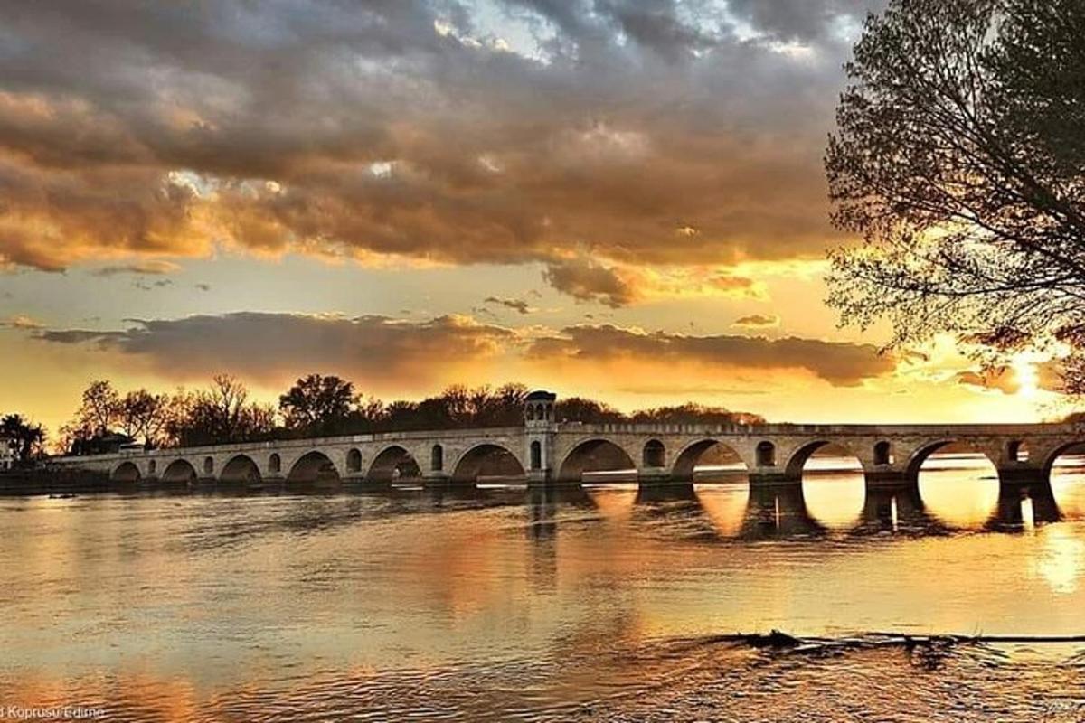 un pont sobre l'aigua amb una posta de sol al fons