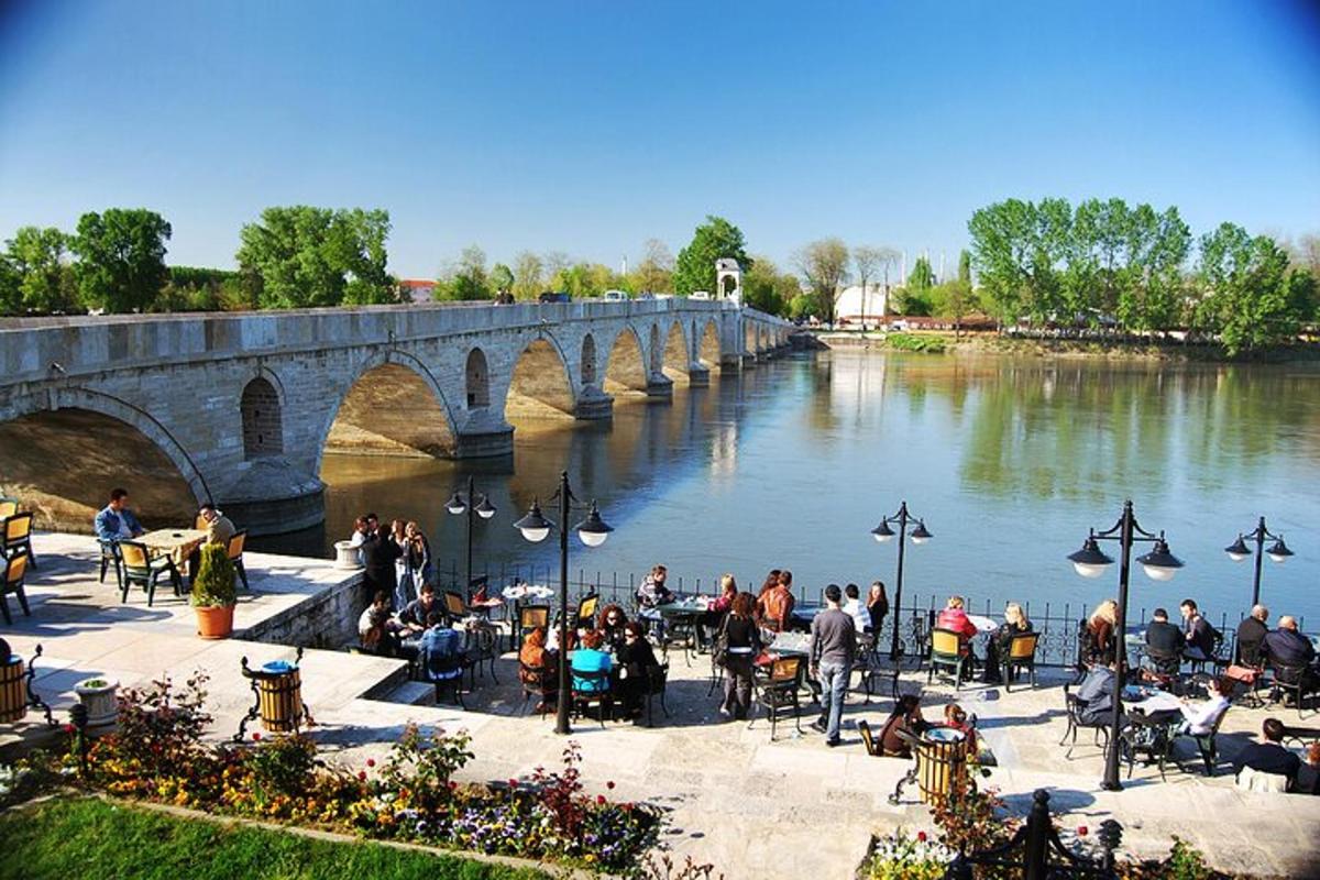 Un grupo de personas sentadas en mesas junto a un puente.