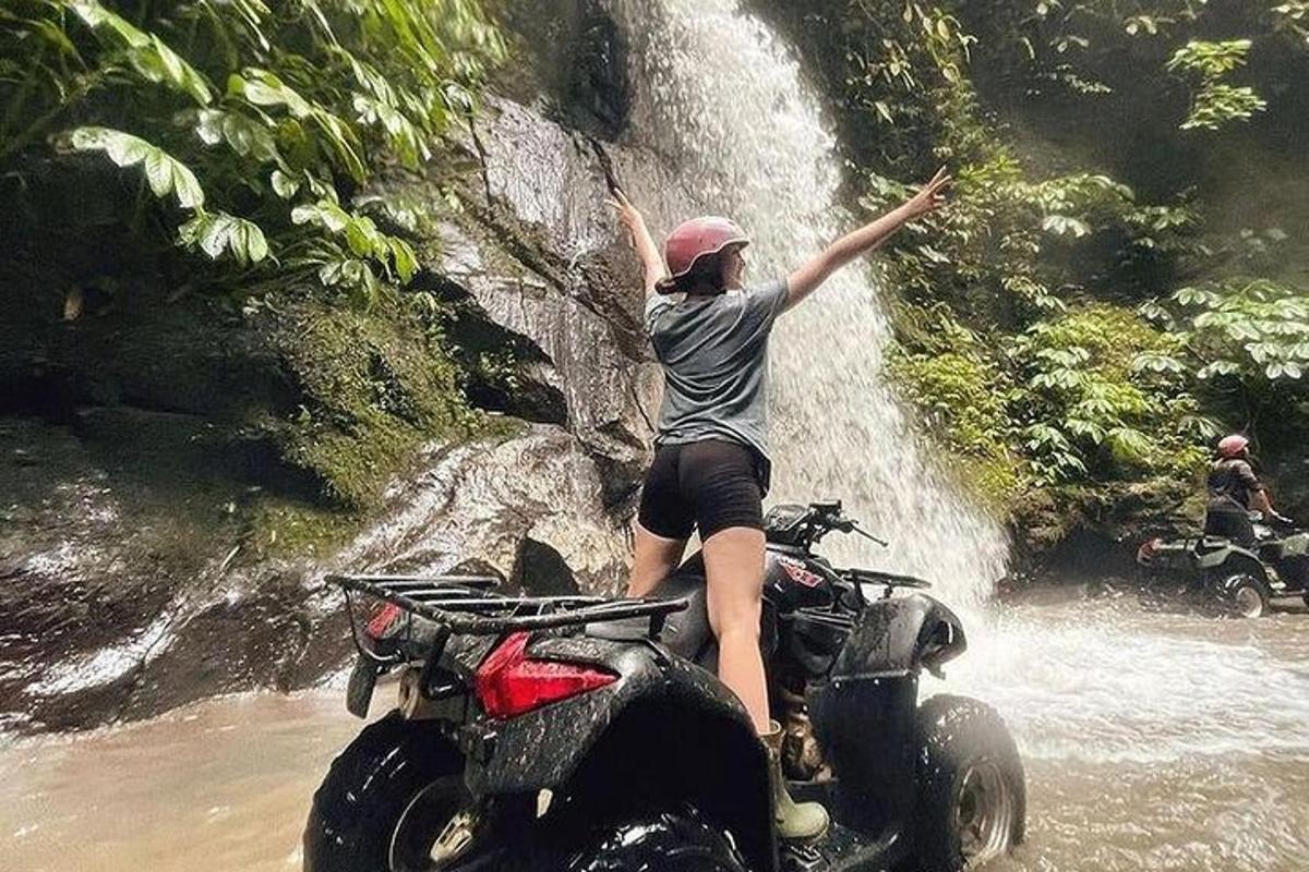 osoba stojící na zadním sedadle motocyklu ve vodopádu