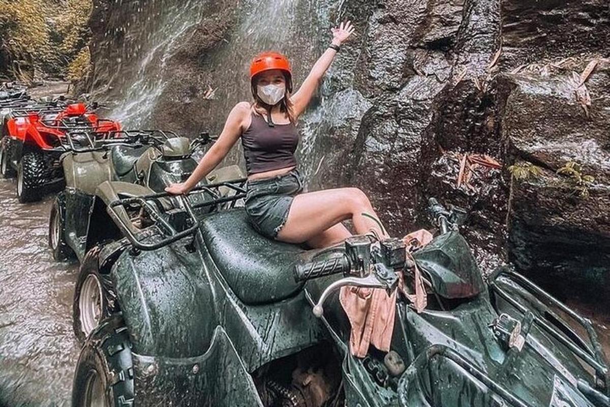 Žena sedí na motorce před vodopádem