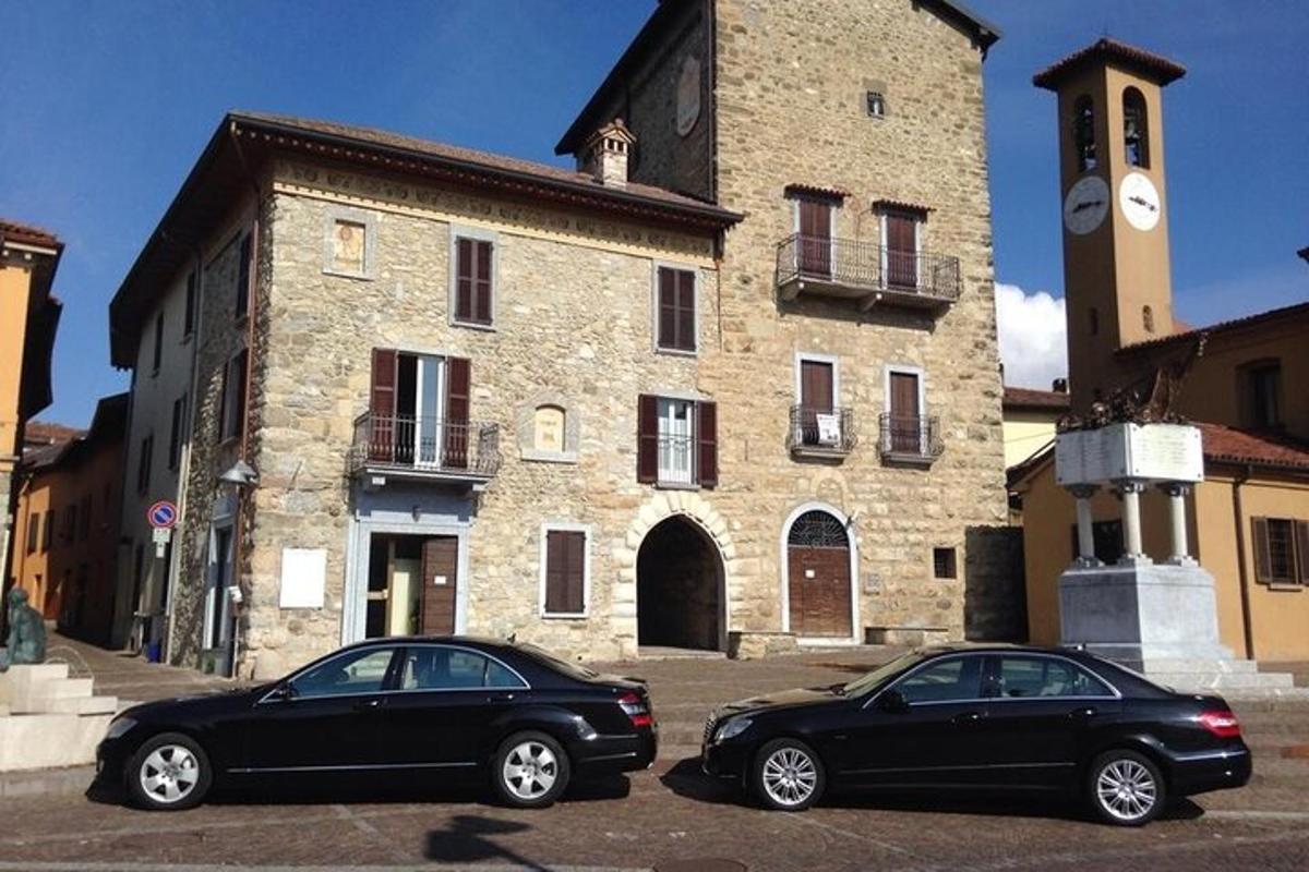 dos cotxes aparcats davant d'un edifici amb una torre de rellotge