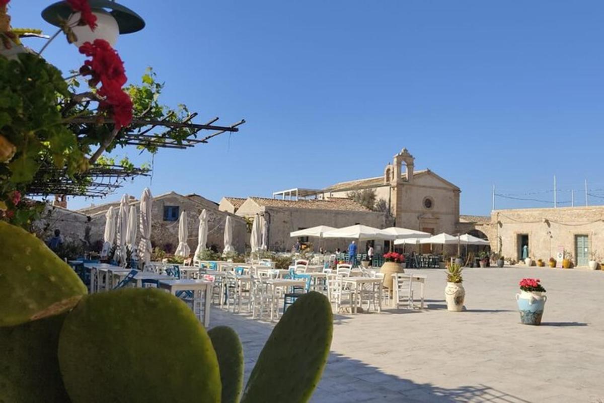 μια βεράντα με λευκές καρέκλες και τραπέζια και κτίρια