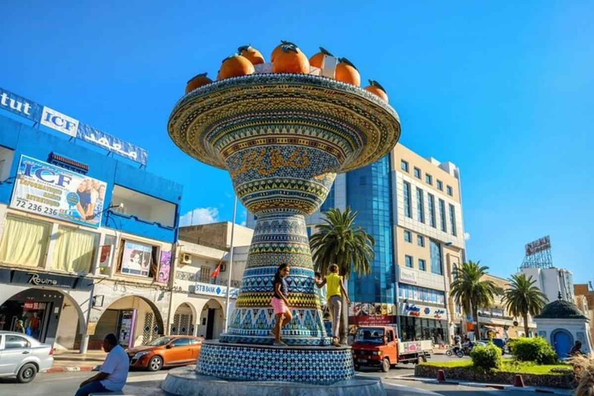 a statue with oranges on top of it on a city street