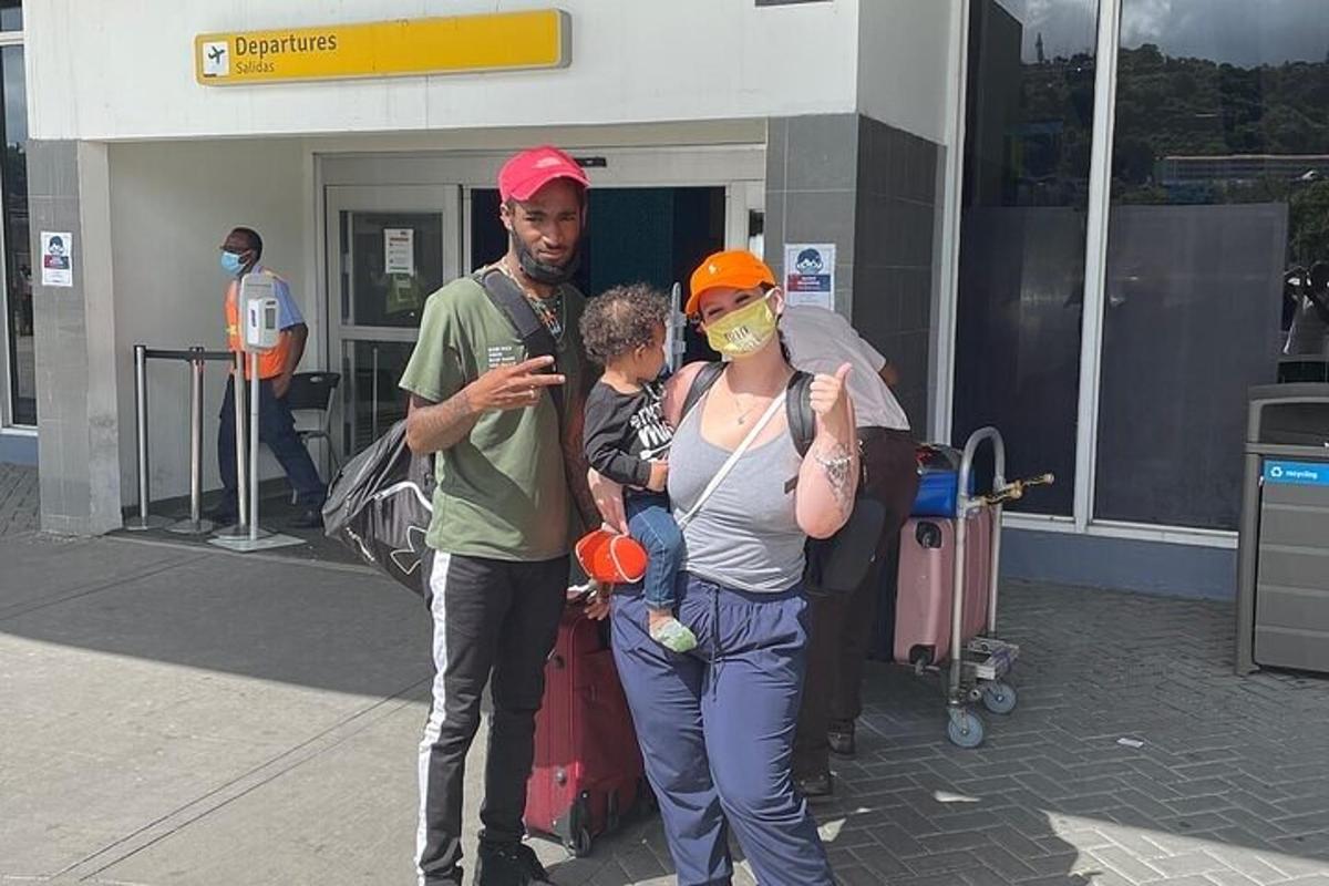 un uomo e una donna che tengono in braccio un bambino in un aeroporto