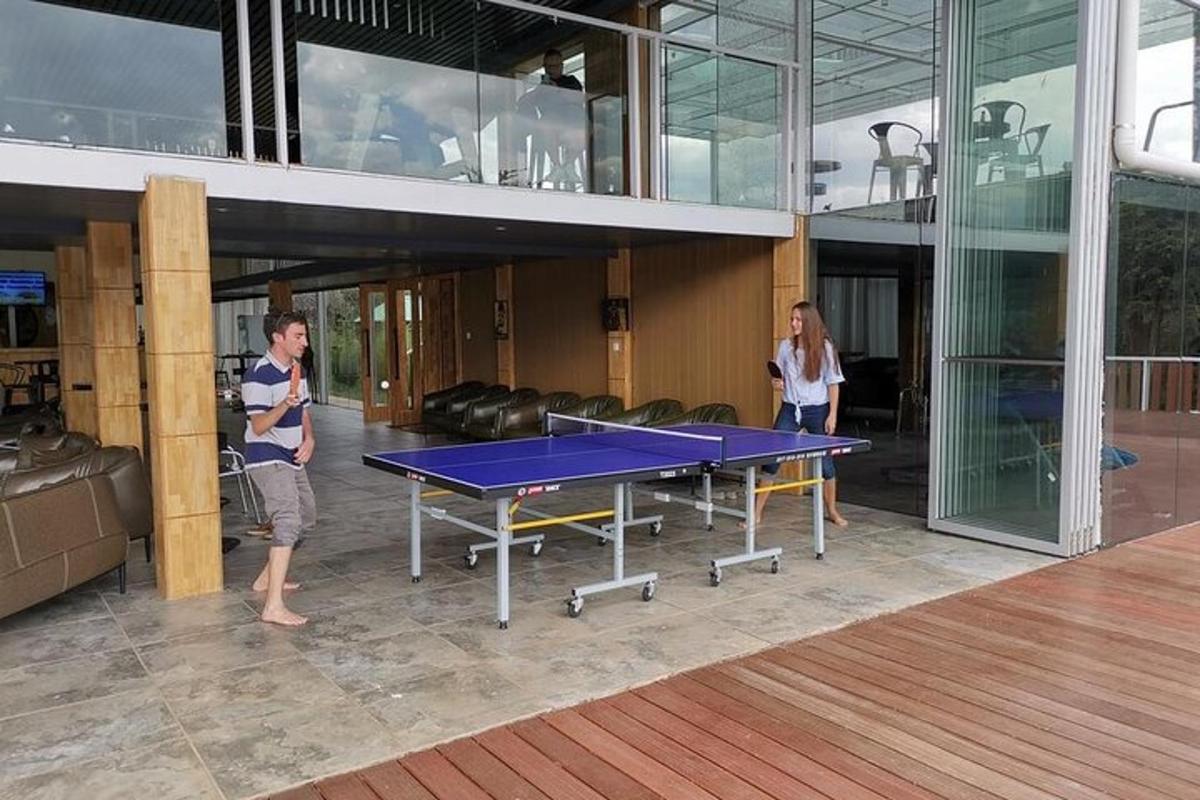 duas pessoas em pé ao redor de uma mesa de pingue-pongue em um prédio