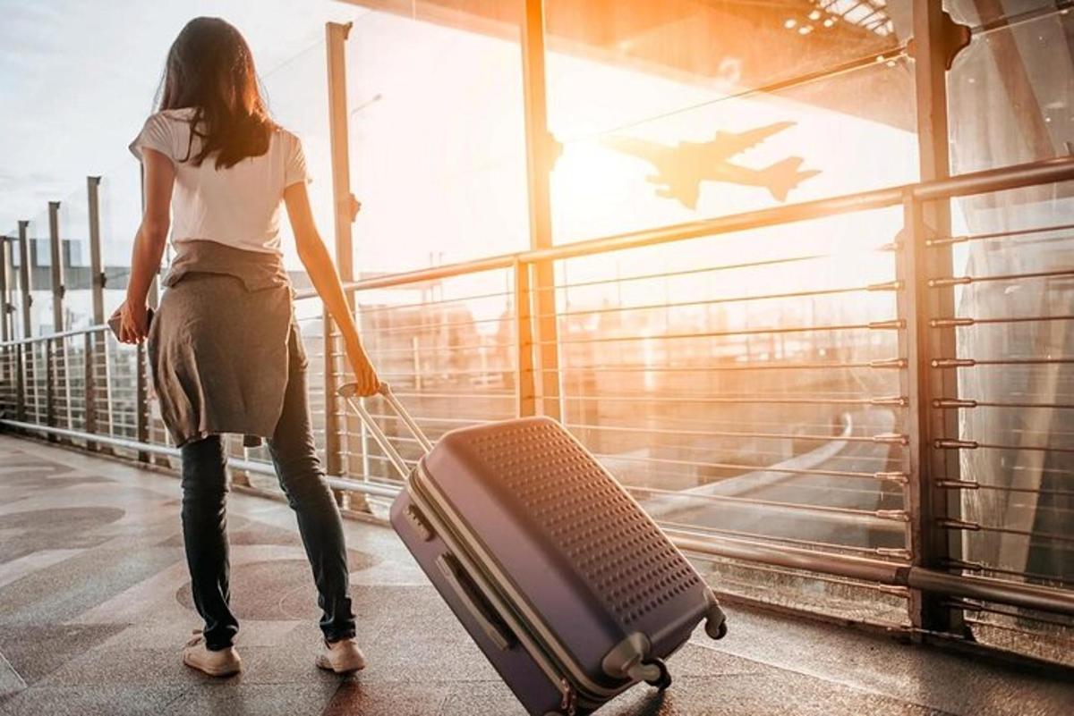 امرأة تمشي بحقيبة سفر في المطار