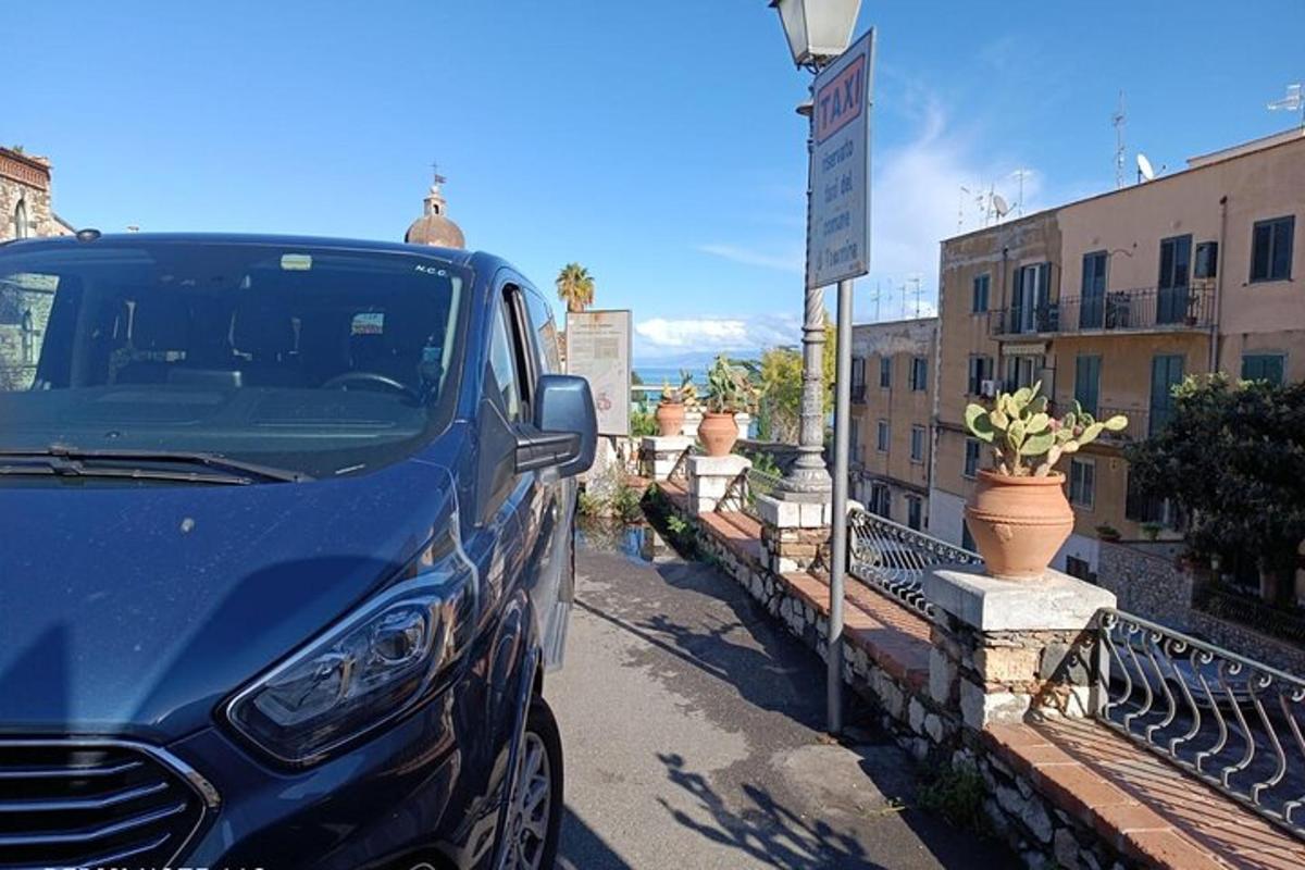 un'auto blu parcheggiata accanto a un cartello stradale