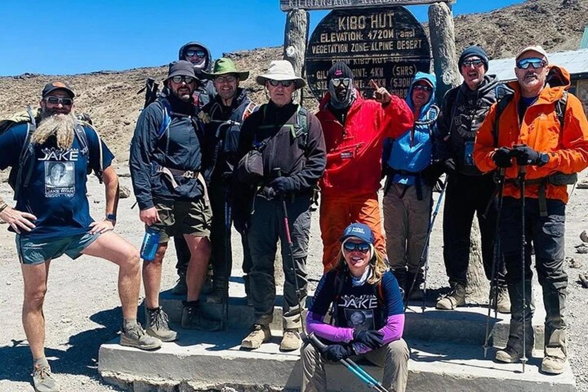 um grupo de pessoas posando para uma foto em frente a uma placa