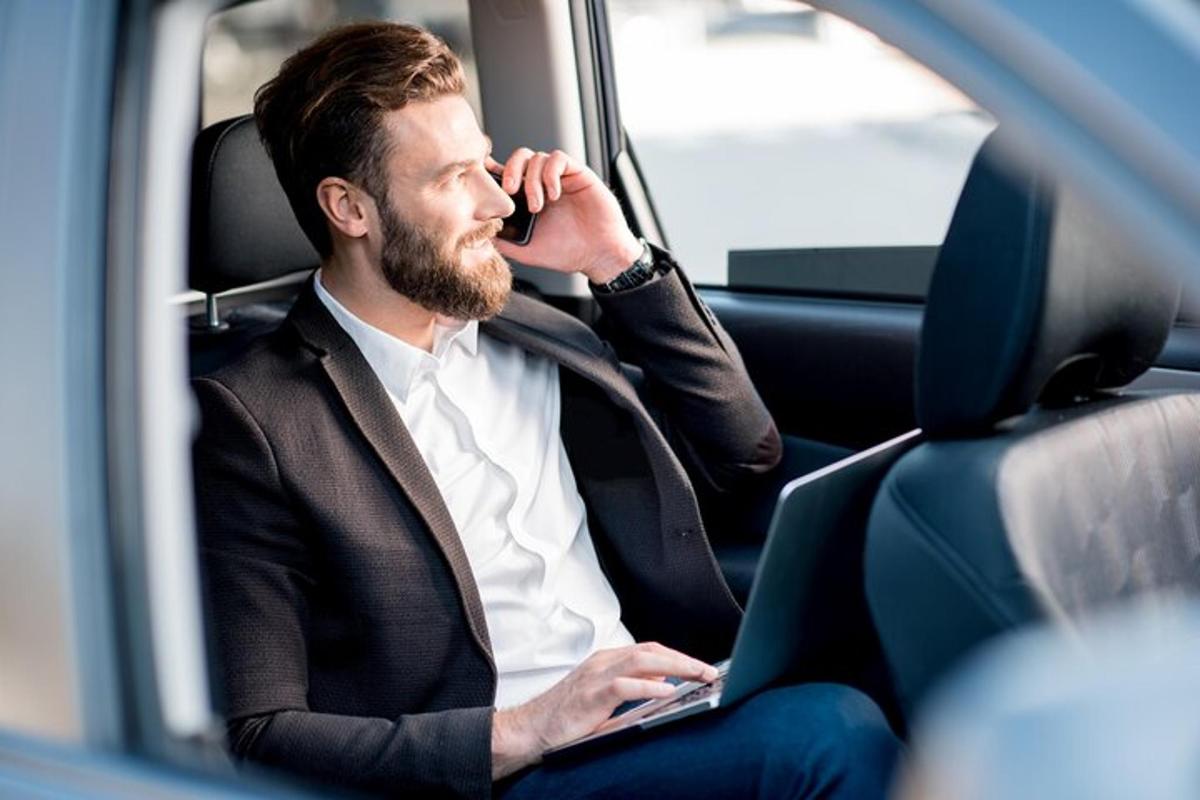 un uomo seduto in macchina mentre parla al cellulare