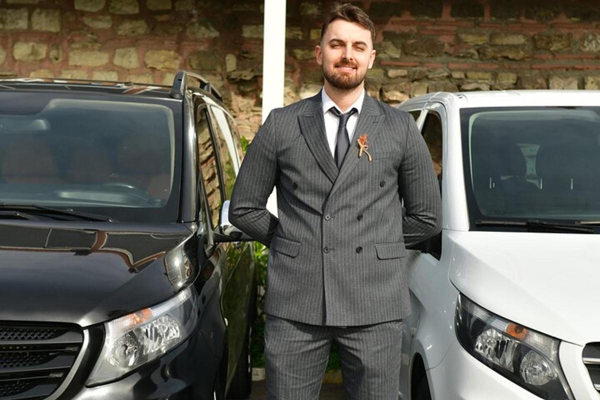 un uomo in giacca e cravatta in piedi accanto a un'auto