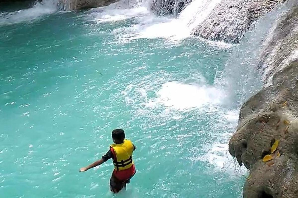 isang lalaking nakatayo sa tubig sa tabi ng talon