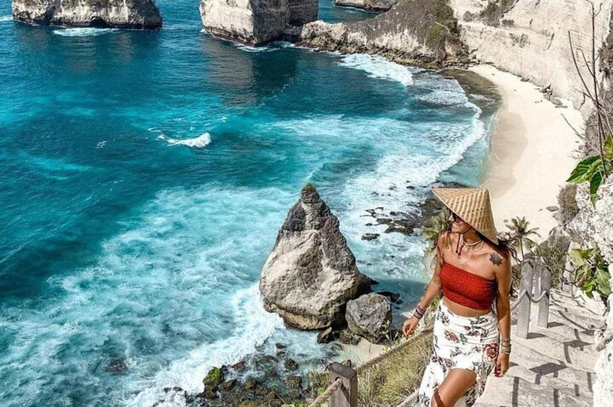 una donna con un cappello in piedi su una sporgenza vicino a una spiaggia