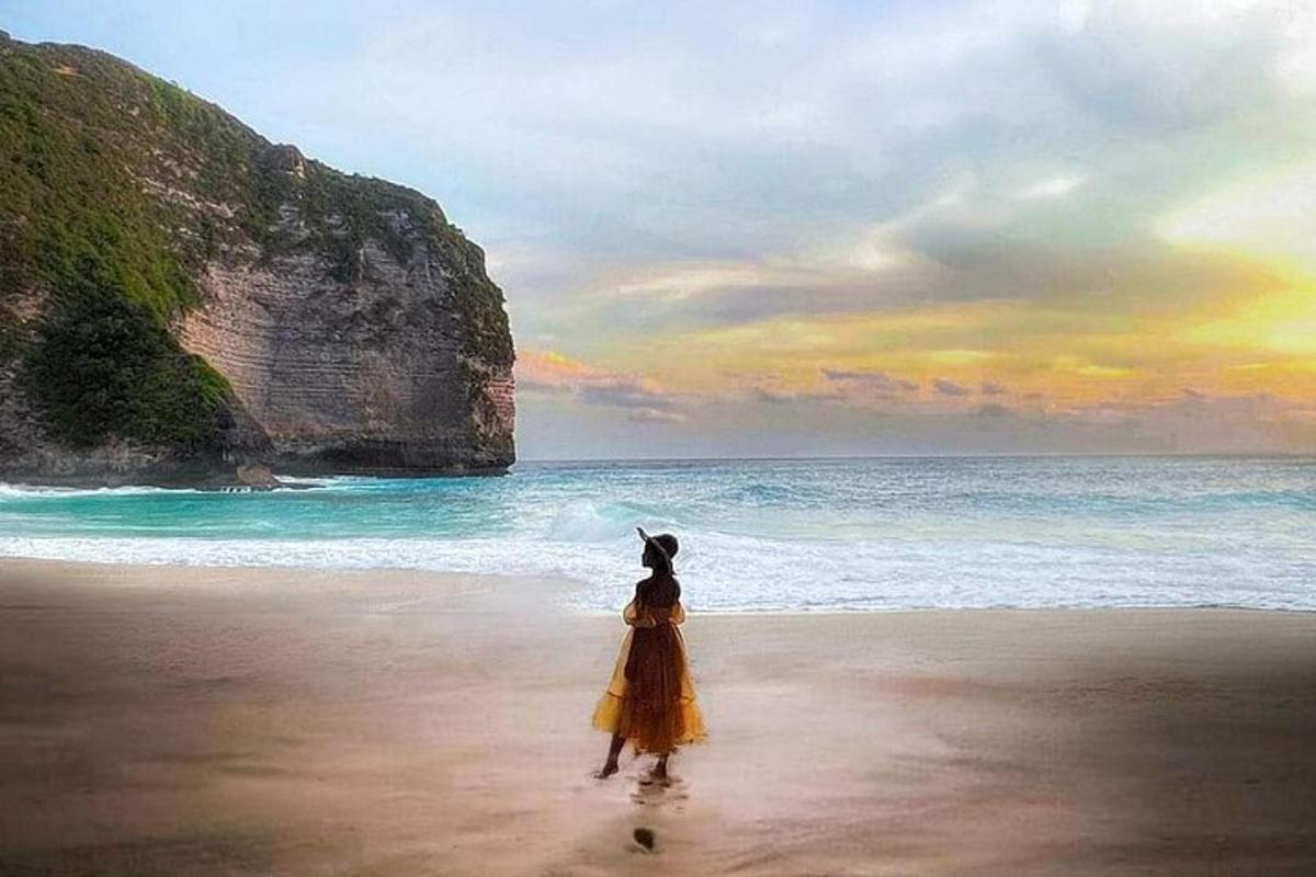a woman in a yellow dress standing on a beach