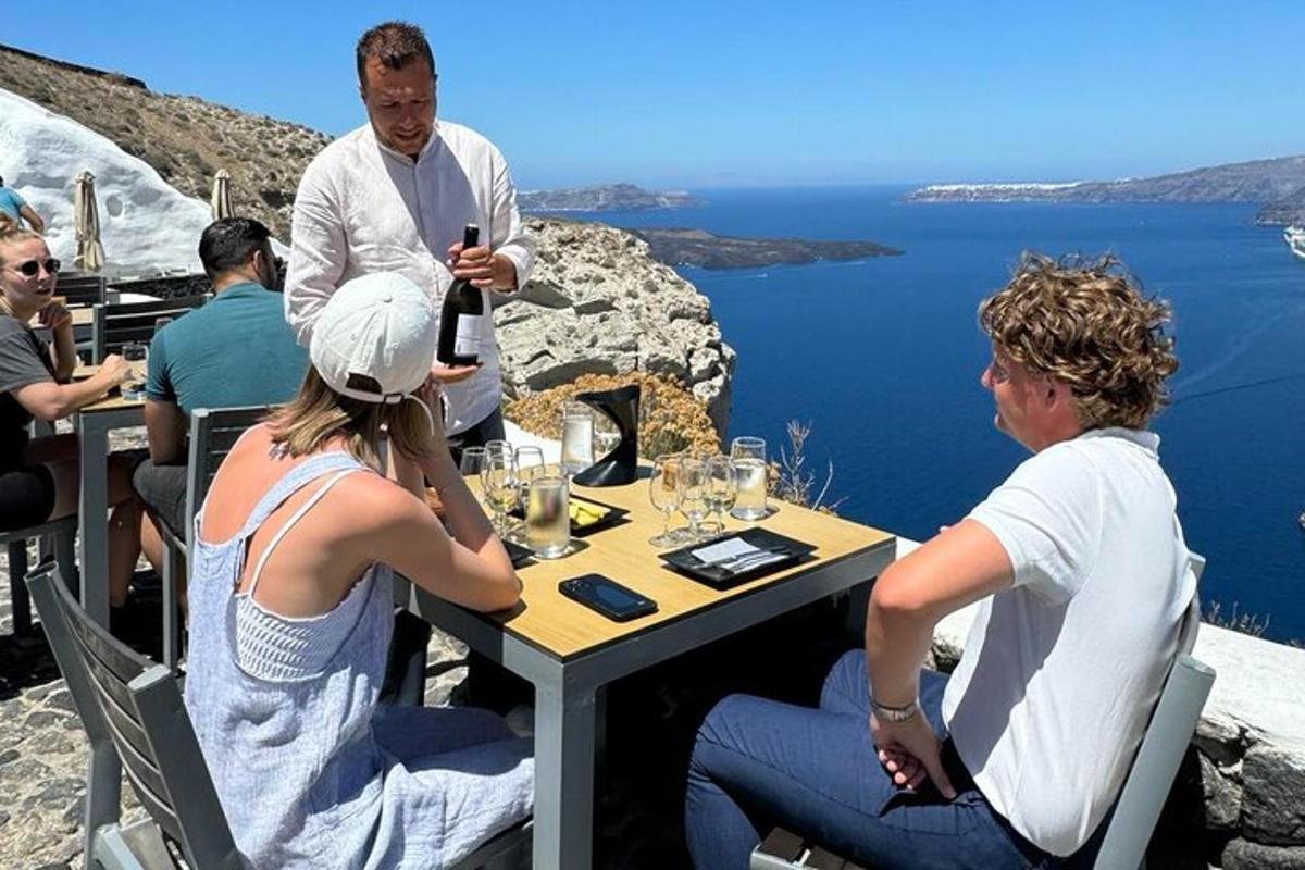 un gruppo di persone sedute a un tavolo con una bottiglia di vino