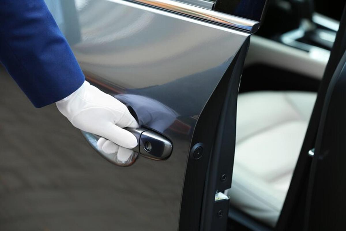 una persona con un guanto bianco che apre la portiera di un'auto