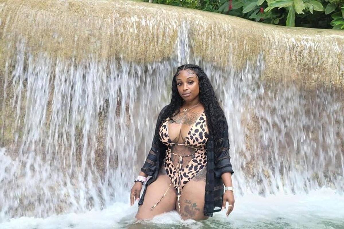 Una mujer parada en el agua frente a una cascada.