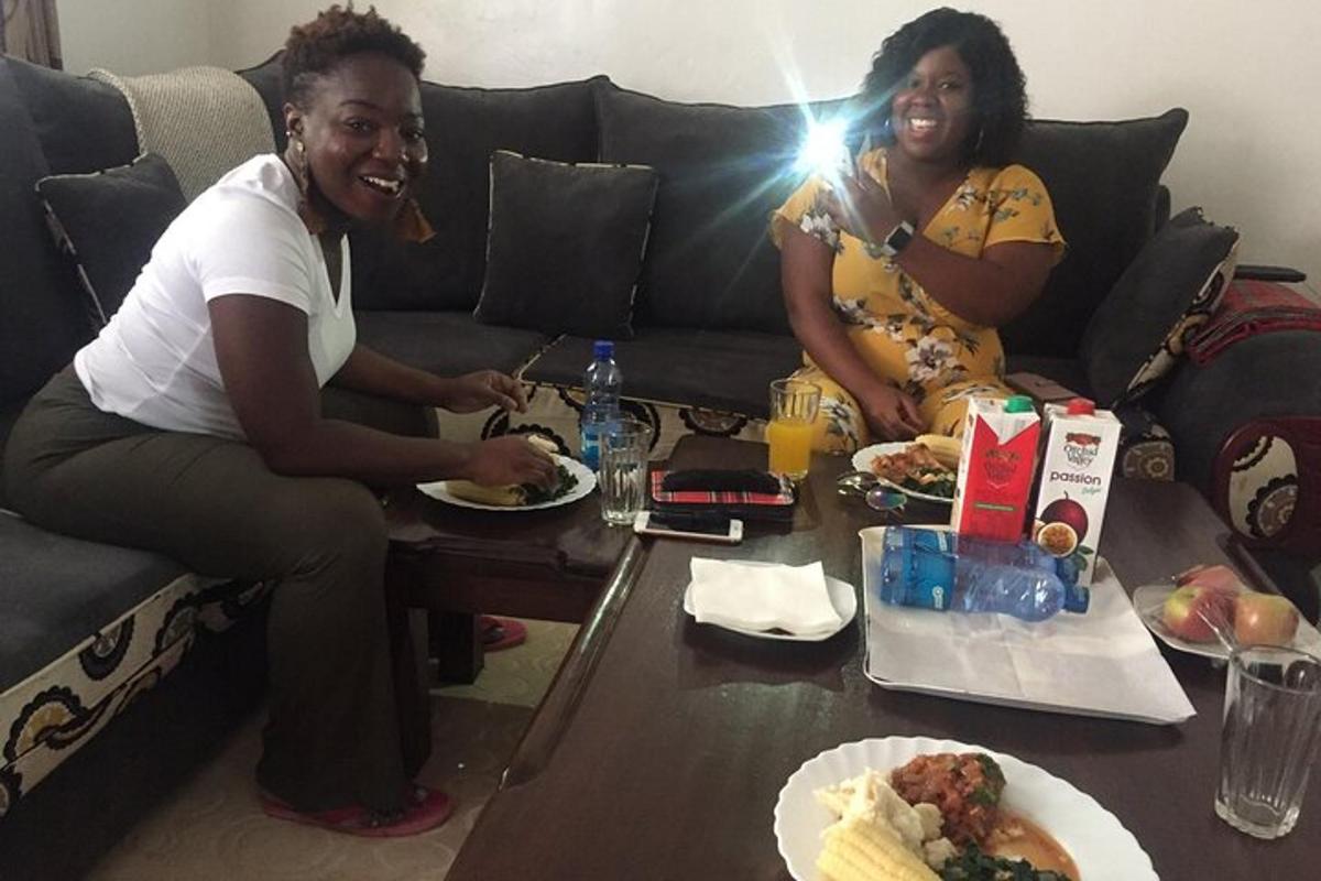 dua wanita duduk di sofa dengan piring berisi makanan