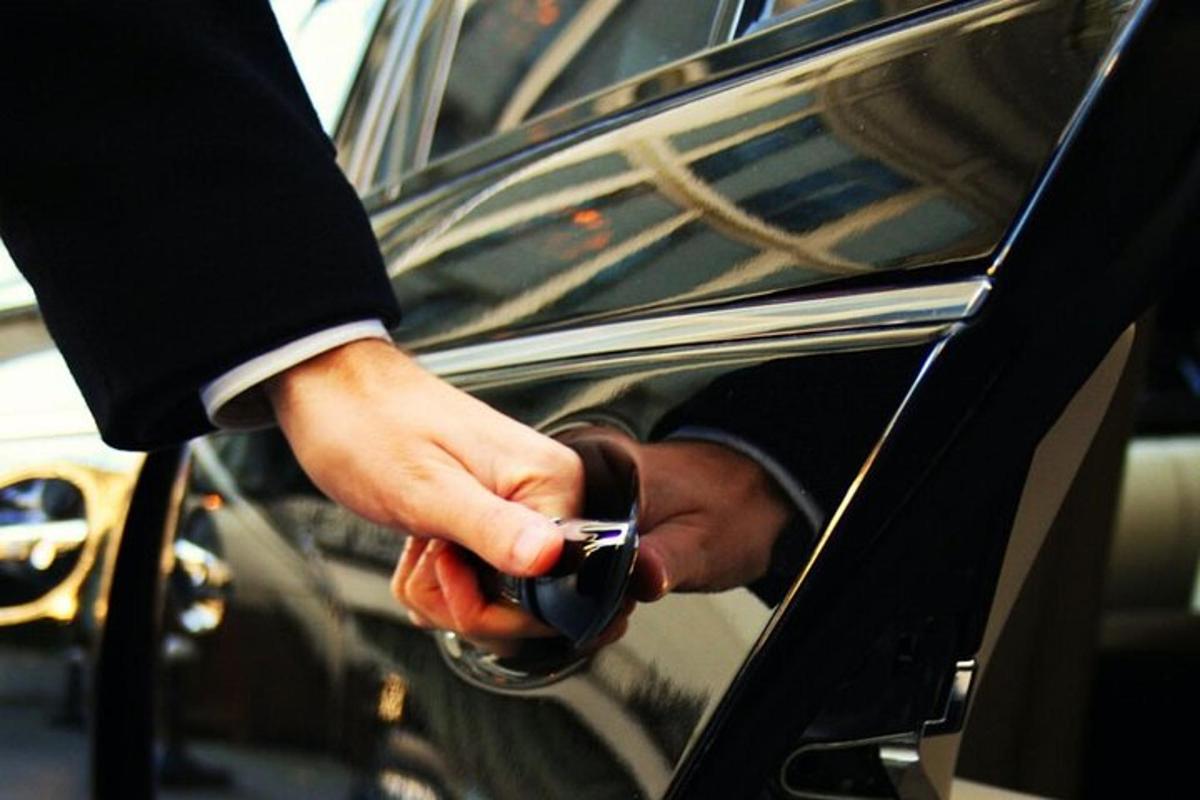 osoba držící mobilní telefon při nastupování do auta