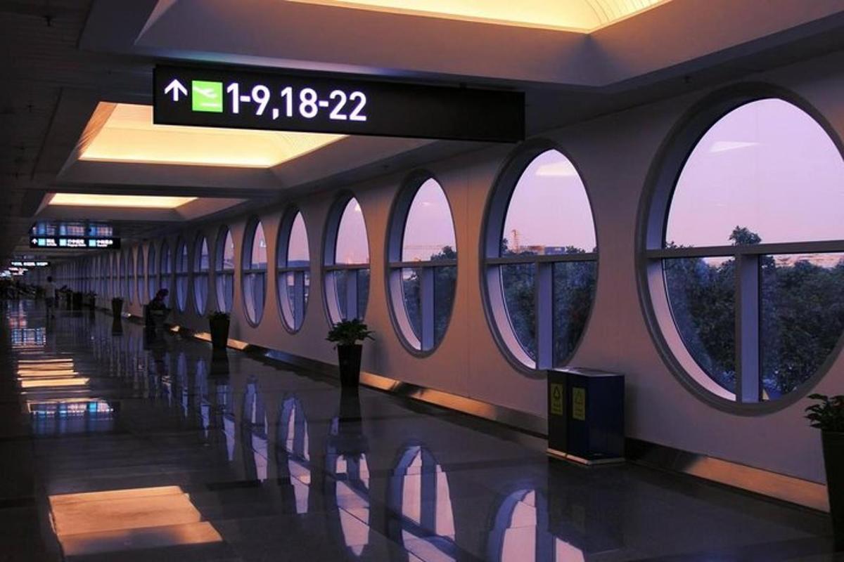 an airport hallway with windows and a clock on the wall