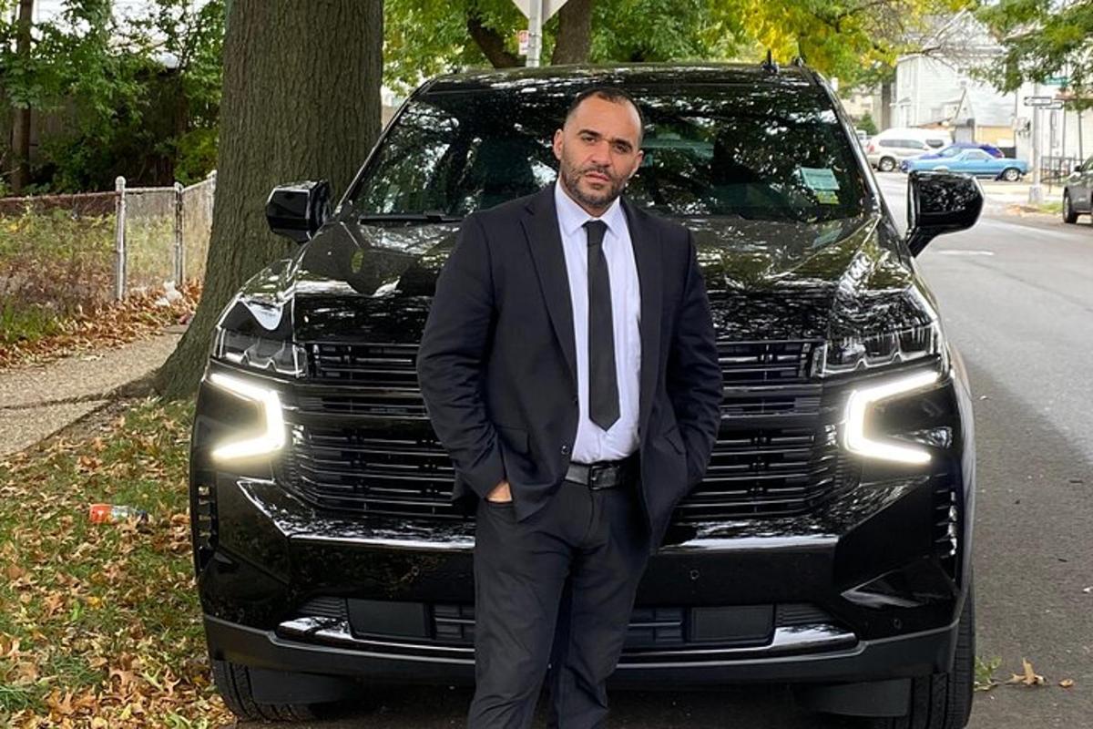 a man in a suit and tie standing in front of a truck