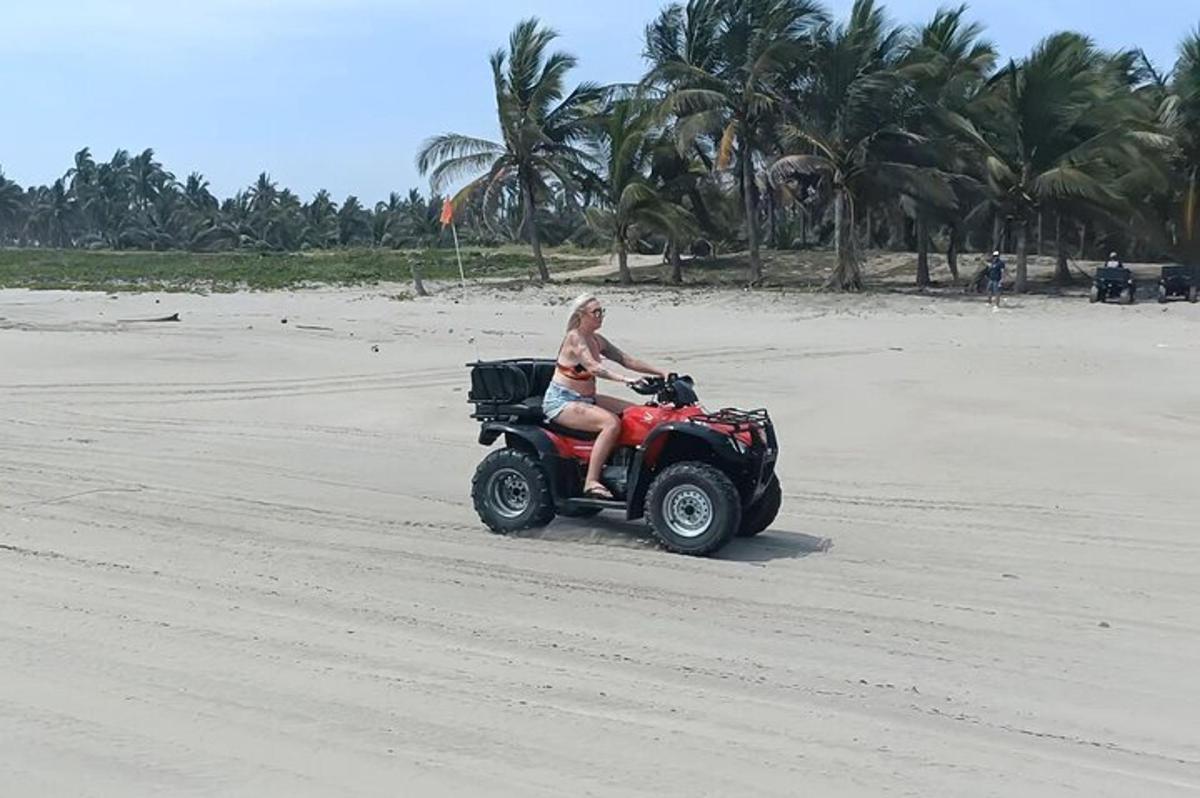 een vrouw die op een quad op het strand rijdt