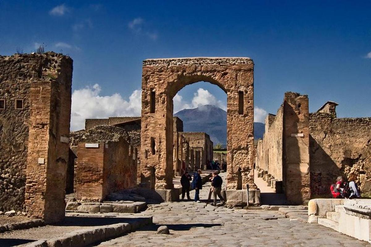 a group of people walking through an arch in the ruins