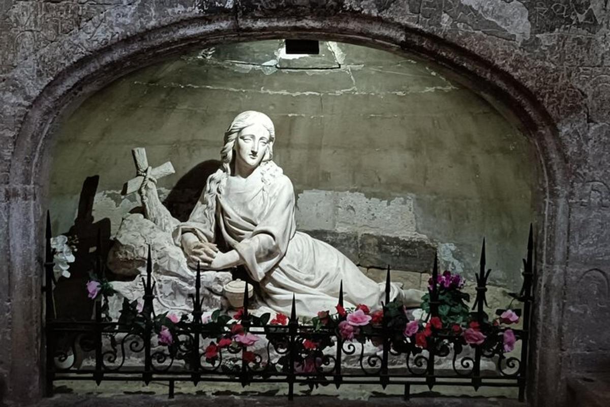 eine Statue einer Frau, die mit Blumen auf einem Zaun sitzt